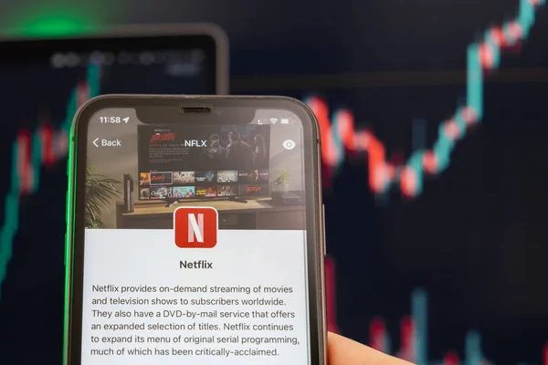 Netflix preço das ações aumentando no mercado de negociação com gráfico de barras gráfico de linha de alta tendência em segundo plano. Homem segurando um telefone celular com logotipo da empresa, fevereiro de 2022, San Francisco, EUA. — Fotografia de Stock