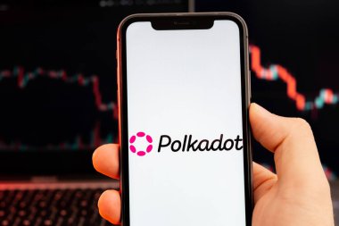 Polkadot DOT kripto para birimi logosu insan eliyle akıllı telefon ekranında kırmızı ışık arka planında eğilim ile birlikte, Şubat 2022, San Francisco, ABD 