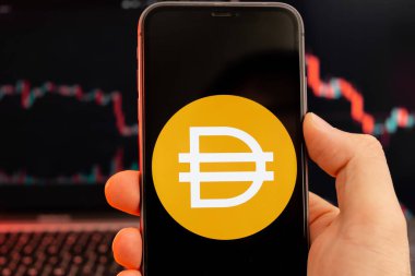 Dai DAI kripto para birimi logosu erkek eliyle akıllı telefon ekranında, kırmızı ışık arka planında eğilim var, Şubat 2022, San Francisco, ABD 