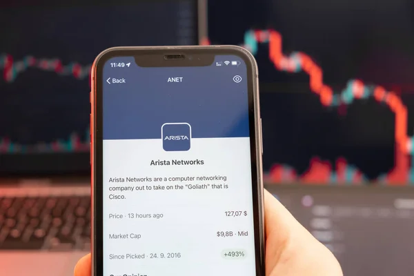 Arista Networks Aktienkurs Abwärtstrend mit roten Graphen auf dem Hintergrund. Männliche Hände halten ein Smartphone mit Logo auf dem Bildschirm, Februar 2022, San Francisco, USA — Stockfoto