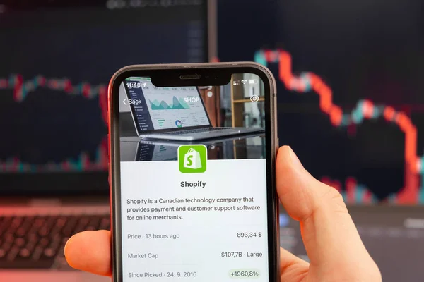 Arka planda kırmızı grafiklerle hisse senedi fiyatlarını düşür. Ekranda logosu olan akıllı telefonu tutan adam elleri, Şubat 2022, San Francisco, ABD