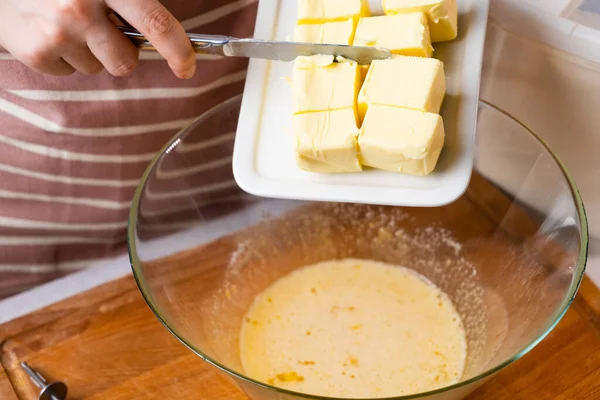 生地の準備プロセス.女性の手は黒の背景にケーキを焼くための混合ボウルにバターを追加します。ペストリーの自家製レシピ — ストック写真
