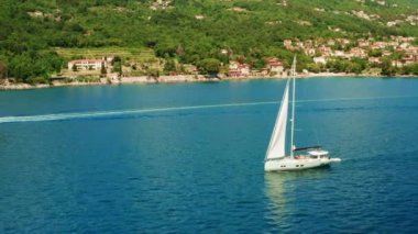 Yelkenli, küçük evleri olan büyük ormancılık adasına doğru yelken açıyor.