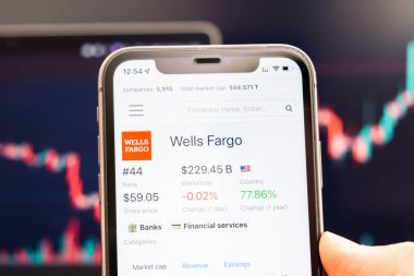 Wells Fargo hisse senedi fiyatı, arka planda değişen borsa grafikleriyle birlikte, Man 's Hand' deki cep telefonu ekranında, Şubat 2022, San Francisco, ABD