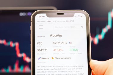 AbbVie hisse senedi fiyatı Man 's Hand ekranında arka planda değişen borsa grafikleriyle birlikte, Şubat 2022, San Francisco, ABD