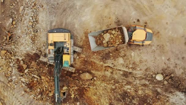 Vista dall'alto escavatore giallo raccoglie minerali dalla fossa aperta e lo carica sul camion — Video Stock