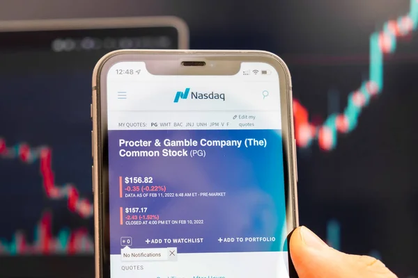 Procter and Gamble Company Logo des Aktienkurses auf dem Bildschirm des Smartphones in der Hand mit sich änderndem Trend auf dem Diagramm im Hintergrund, Februar 2022, San Francisco, USA — Stockfoto