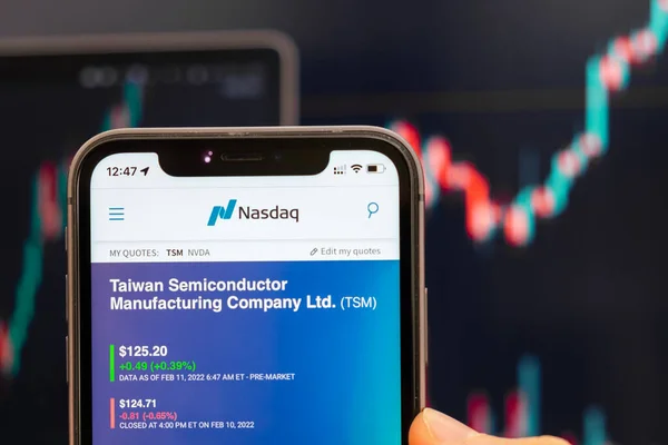 Taiwan Semiconductor Manufacturing TSM-Logo des Aktienkurses auf dem Bildschirm des Smartphones in der Hand mit sich änderndem Trend auf dem Chart im Hintergrund, Februar 2022, San Francisco, USA — Stockfoto