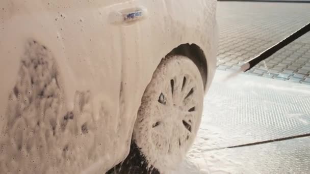 Опрыскивание белой мыльной пены со стороны автомобиля на участке на городской улице — стоковое видео