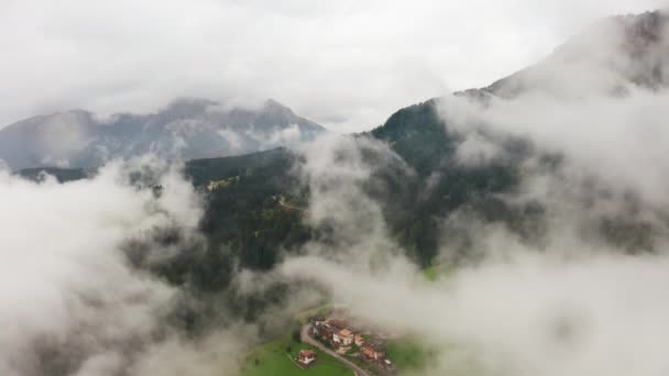 Voando através de nuvens sobre o vale dos Alpes com antena da aldeia — Vídeo de Stock