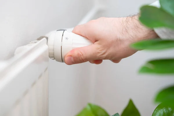 人の手は暖房の費用を減らすために暖房ラジエーターの温度ノブを調節する. — ストック写真