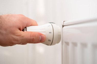 İnsan eli ısıtma maliyetlerini düşürmek için ısıtma radyatörünün ısı düğmesini düzenler..
