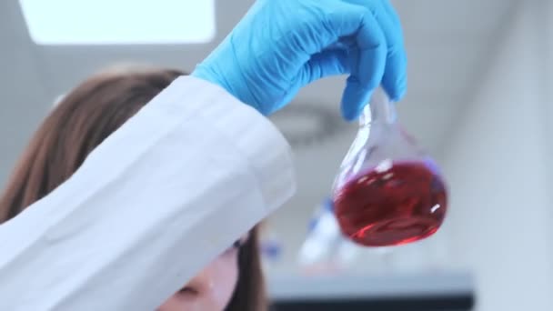 A laboratóriumi dolgozó folyadékkal rázza meg a lombikot tudományos kutatás céljából. — Stock videók