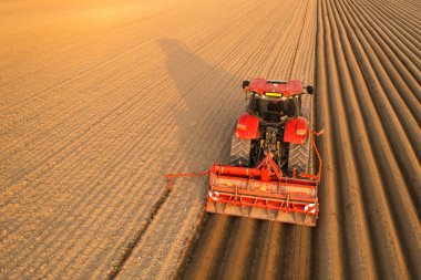 Traktör, geride uzun izler bırakmak için tarlayı sürükler.