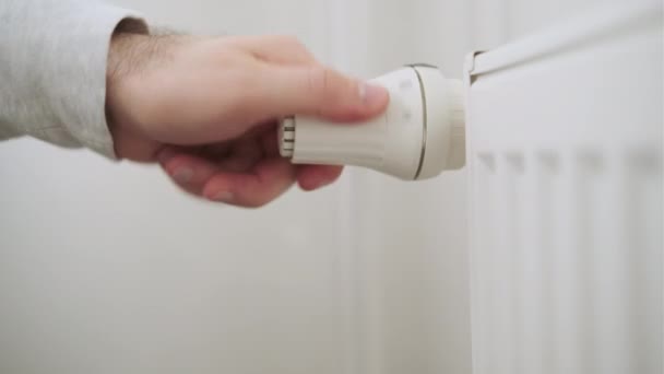 Рука человека регулирует температурную ручку радиатора отопления для отопительной комнаты — стоковое видео