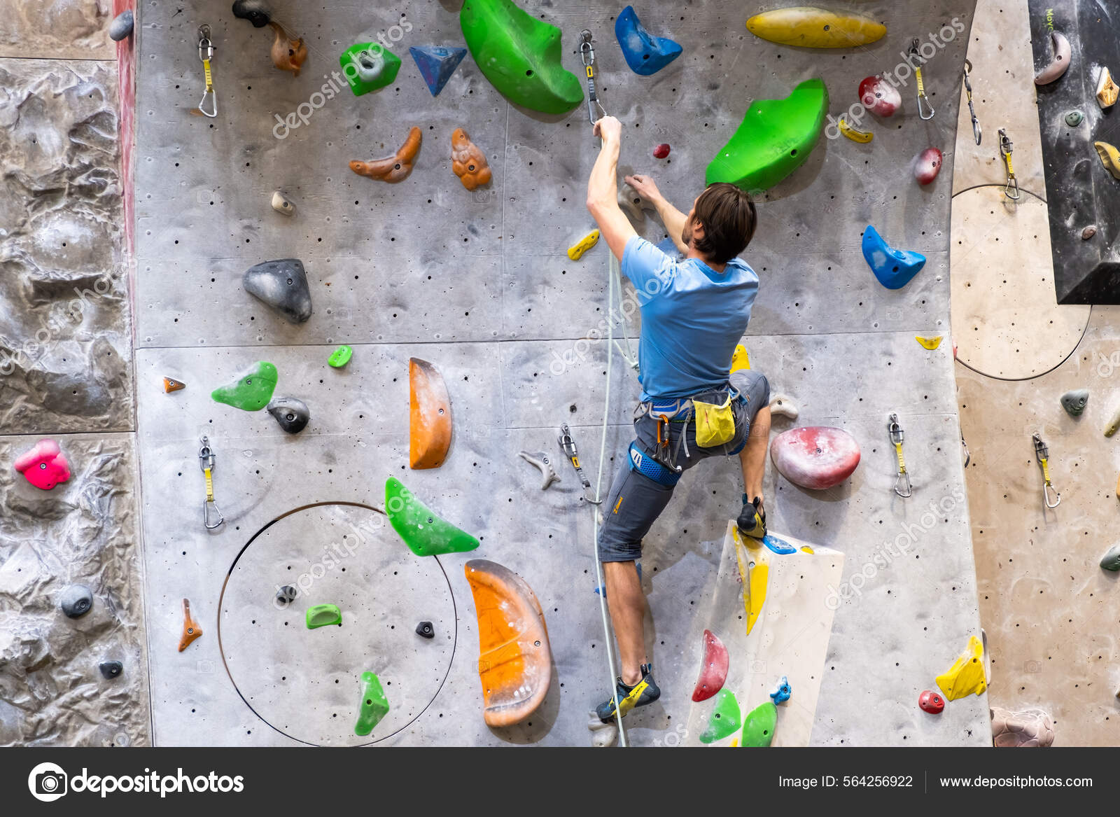 The climber trains on the artificial rock wall with insurance in