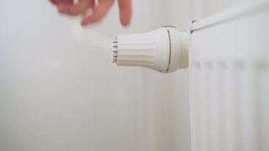 İnsan eli ısıtma maliyetlerini düşürmek için ısıtma radyatörünün ısı düğmesini düzenler..