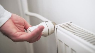 İnsan eli ısıtma maliyetlerini düşürmek için ısıtma radyatörünün ısı düğmesini düzenler..