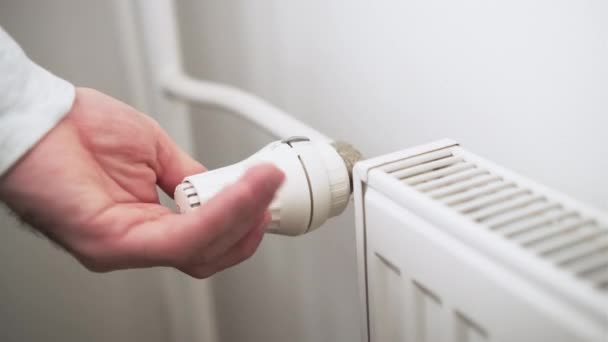 De hand van de mens regelt temperatuurknop van verwarmingsradiator om verwarmingskosten te verminderen. — Stockvideo