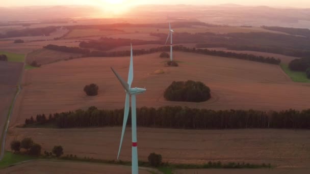 Windräder erzeugen Energie auf abgeernteten Feldern bei Sonnenuntergang — Stockvideo