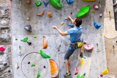 Tırmanışçı yapay kaya duvarında, kayalık jimnastik salonunda sigorta yaptırıyor.