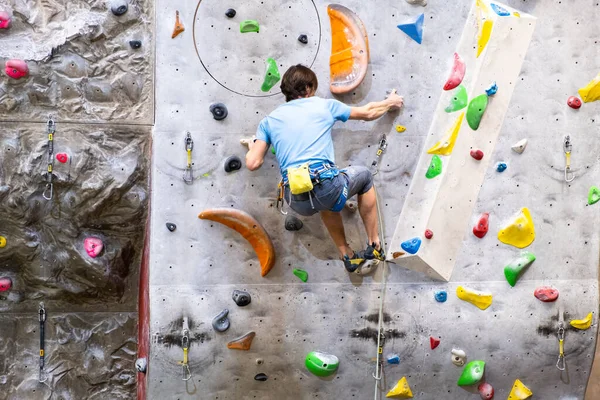 Le grimpeur s'entraîne sur la paroi rocheuse artificielle avec assurance dans le gymnase de bloc — Photo