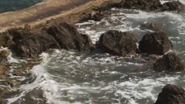 Plajda ıslak kayalar Yazın fırtınalı deniz dalgalarıyla yıkanır