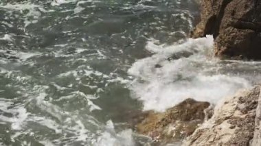 Vahşi sahildeki kayalar, parlak güneş ışığında fırtınalı denizlerle yıkanır.