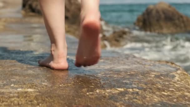 Kvinna promenader längs sten havet nära stranden tvättas av vågor — Stockvideo