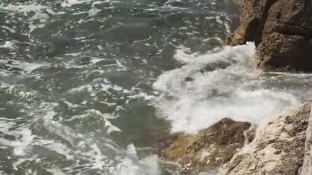 Rochers sur la plage sauvage baignés par la mer orageuse à la lumière du soleil — Video