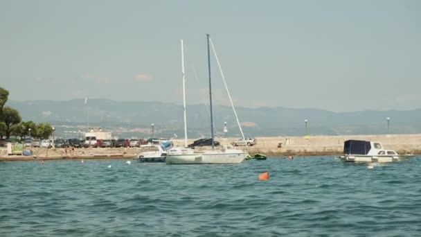 Moored yachts and motorboats rock on water surface near pier — Vídeos de Stock