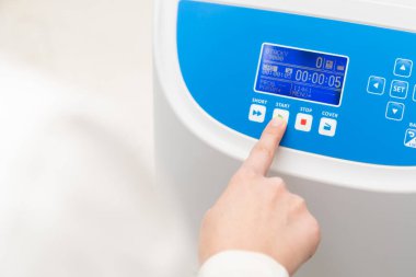 Kadın örnek hazırlamak için santrifüjün düğmesine basıyor..