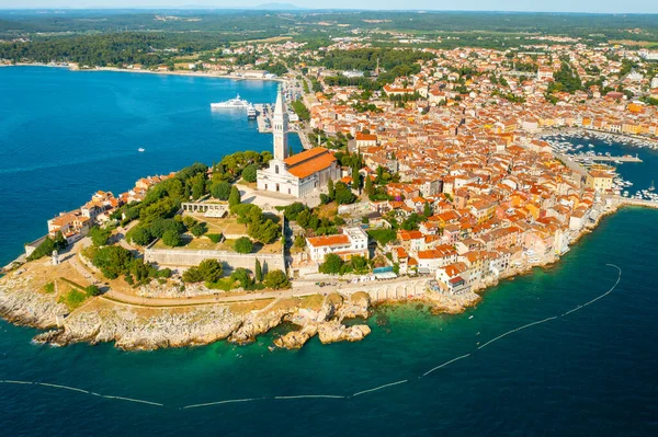 Cerco de Rovinj e torre de igreja de Santa Eufêmia. Edifícios da cidade croata perto de florestas e mar Adriânico à luz do sol brilhante. Panorama aéreo — Fotografia de Stock