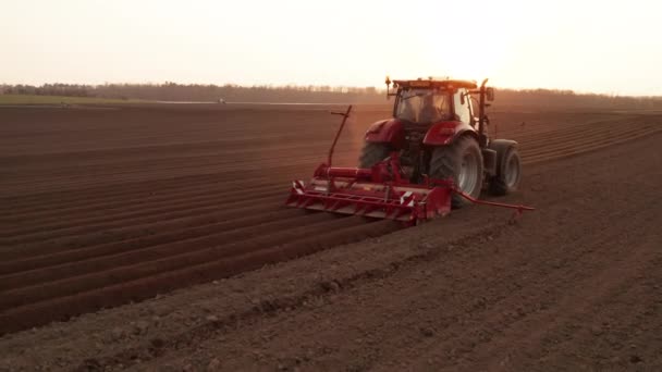 Zeitgenössischer Traktor zieht Stecker und macht bei Sonneneinstrahlung Furchen auf dem Feld. — Stockvideo