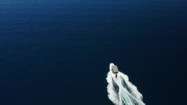 Повітряний безпілотник знімок моторного човна, що пливе в морі з темно-синьою водою, що ріже хвилю — стокове відео