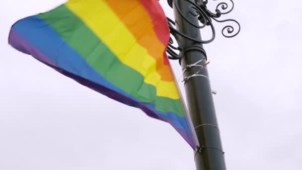 Brillante bandera LGBT unida a flautas de poste negro en el viento — Vídeos de Stock