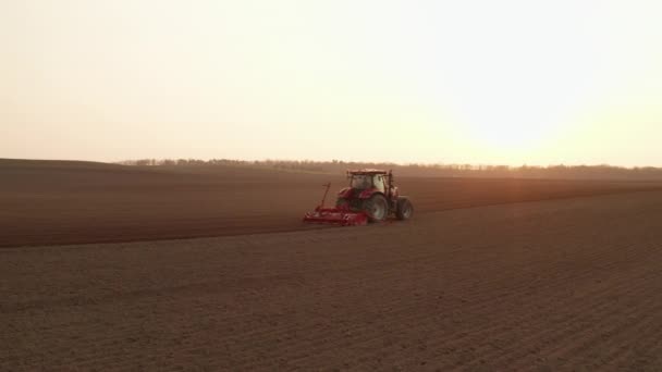 Современный трактор тащит вилку, делая борозды на почве в поле при солнечном свете. — стоковое видео