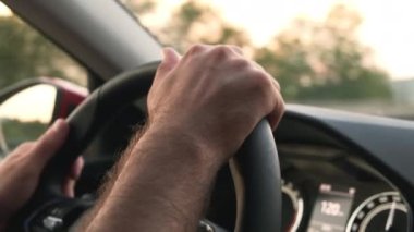 Driver holds steering wheel of car driving in highland