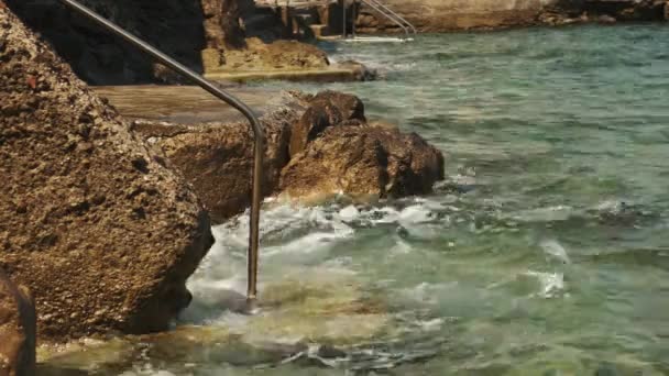 Морские волны разбивают металлические лестницы и перила, построенные для пловцов — стоковое видео
