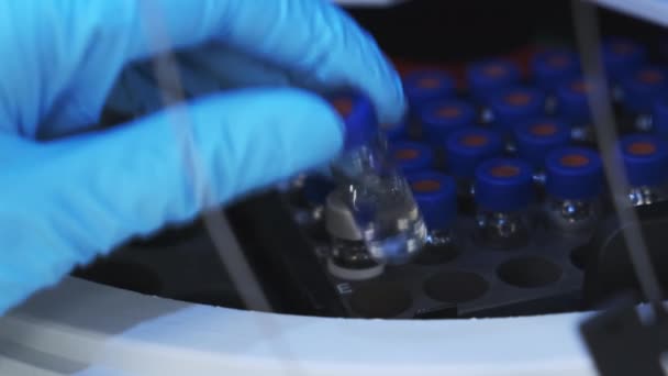 Scientist in rubber gloves puts HPLC vials into the auto sample for measuremetns — Stock Video