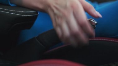 Bir kadının eli bir düğmeye basar ve el frenini indirir.