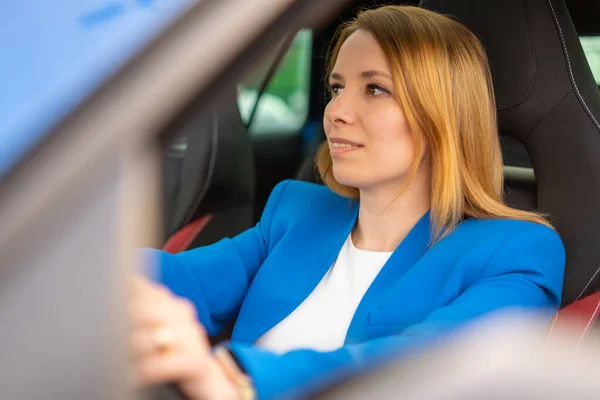Business woman driving car in the blue suit.