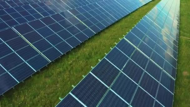 田舎の草の上に構築された表面に反映空を持つ未来的な太陽電池パネル 太陽電池はステーションの近くで代替エネルギーを発生させます — ストック動画