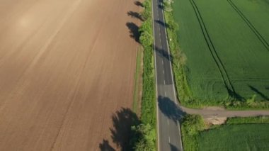 Otoyoldaki motosikletliler tarlalar ve ekilen tarlalar arasında geriliyorlar. Gün batımında sınırsız gelişmiş tarım manzarası kuş bakışı