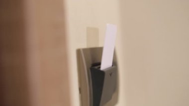 Female person hand with blue manicure takes hotel key card from room card holder. Woman takes card to leave room on blurry background closeup