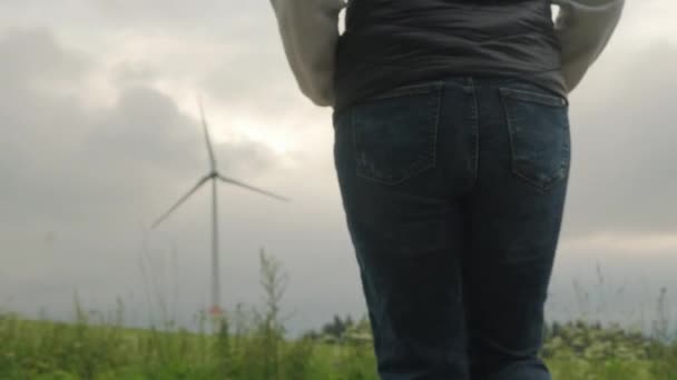 Person Walks Grass Looking Functioning Windmill Closeup Wind Turbine Produces — Vídeo de stock