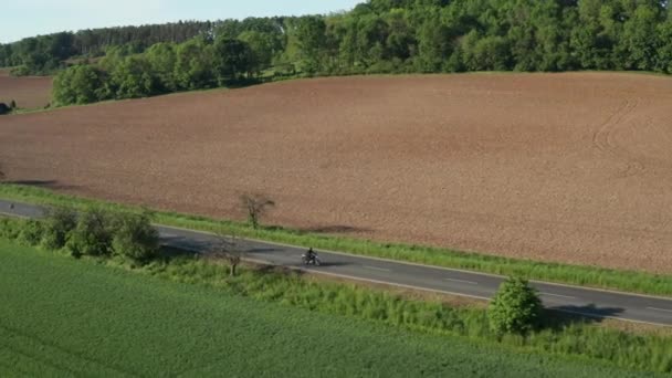 Motorbiker Rides Empty Road Yellow Ripe Field Sunset Trees Cast — Stockvideo