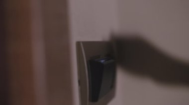 Female person hand puts back key card into room card holder. Woman putting key card switches on light in hotel room on blurry background closeup