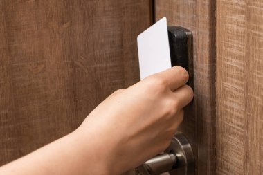 Woman hand puts key card to panel opening hotel room door. 