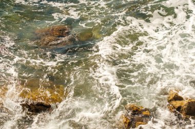 Sea waves breaking on rocks and hitting the shore.